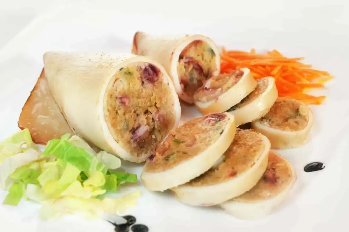 Seppie ripiene, un piatto gustoso con un ripieno ricco e colorato, servite con insalata fresca e carote julienne.
