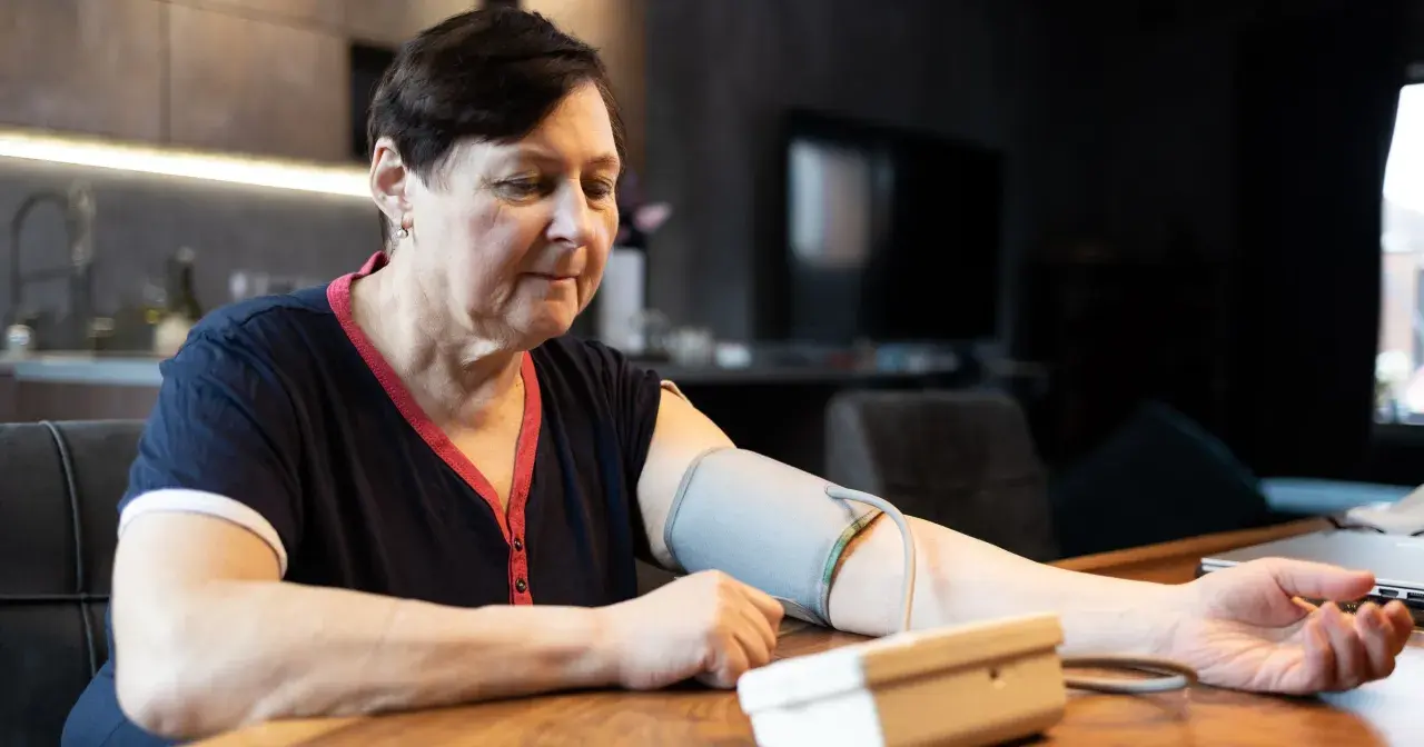 Kobieta w średnim wieku mierzy ciśnienie. Dba o prawidłowe ciśnienie tętnicze u 50-latka, monitorując je w domu.