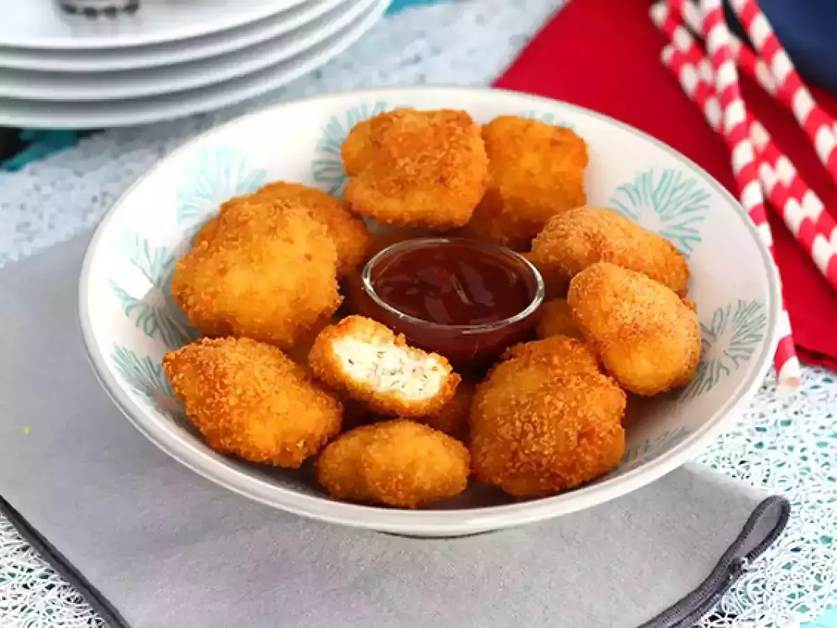 En skål med gyllene chicken nuggets och en liten skål med ketchup. Perfekt för en snabb och god måltid.