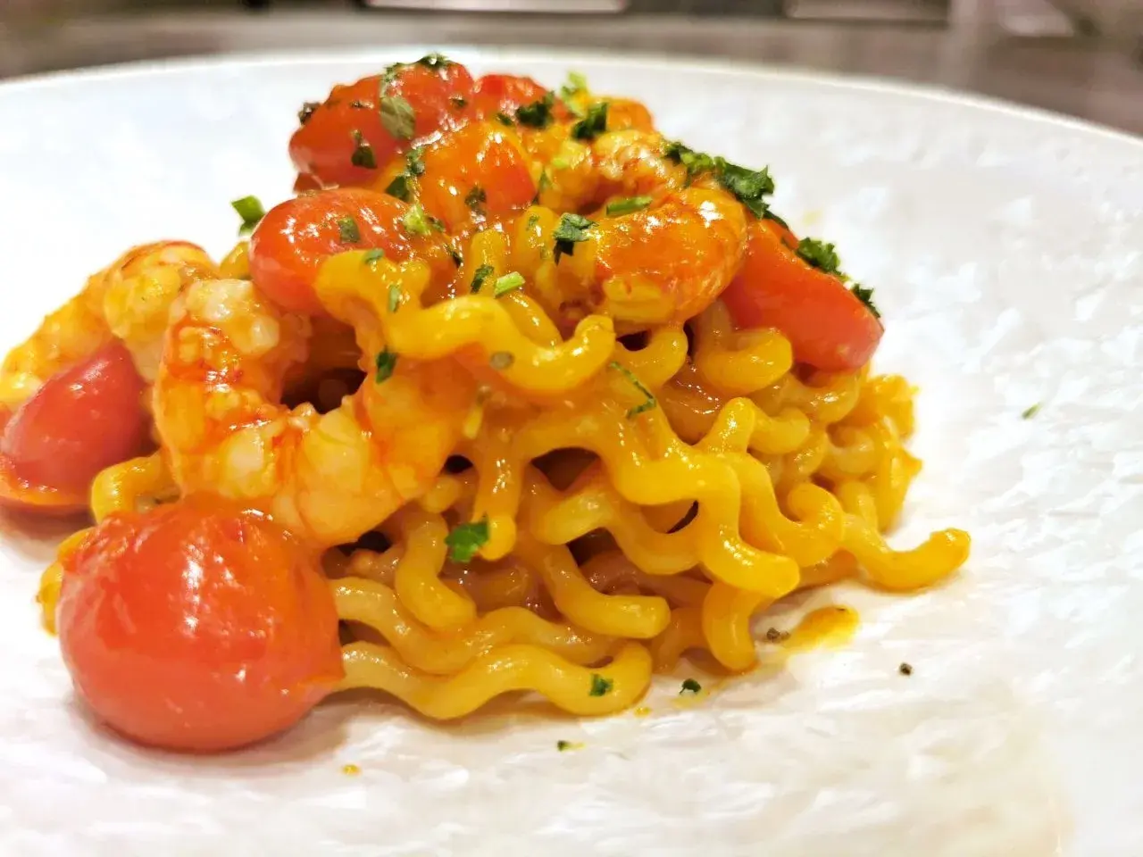 Un piatto invitante di pasta con gamberetti, pomodorini succosi e un tocco di prezzemolo fresco.