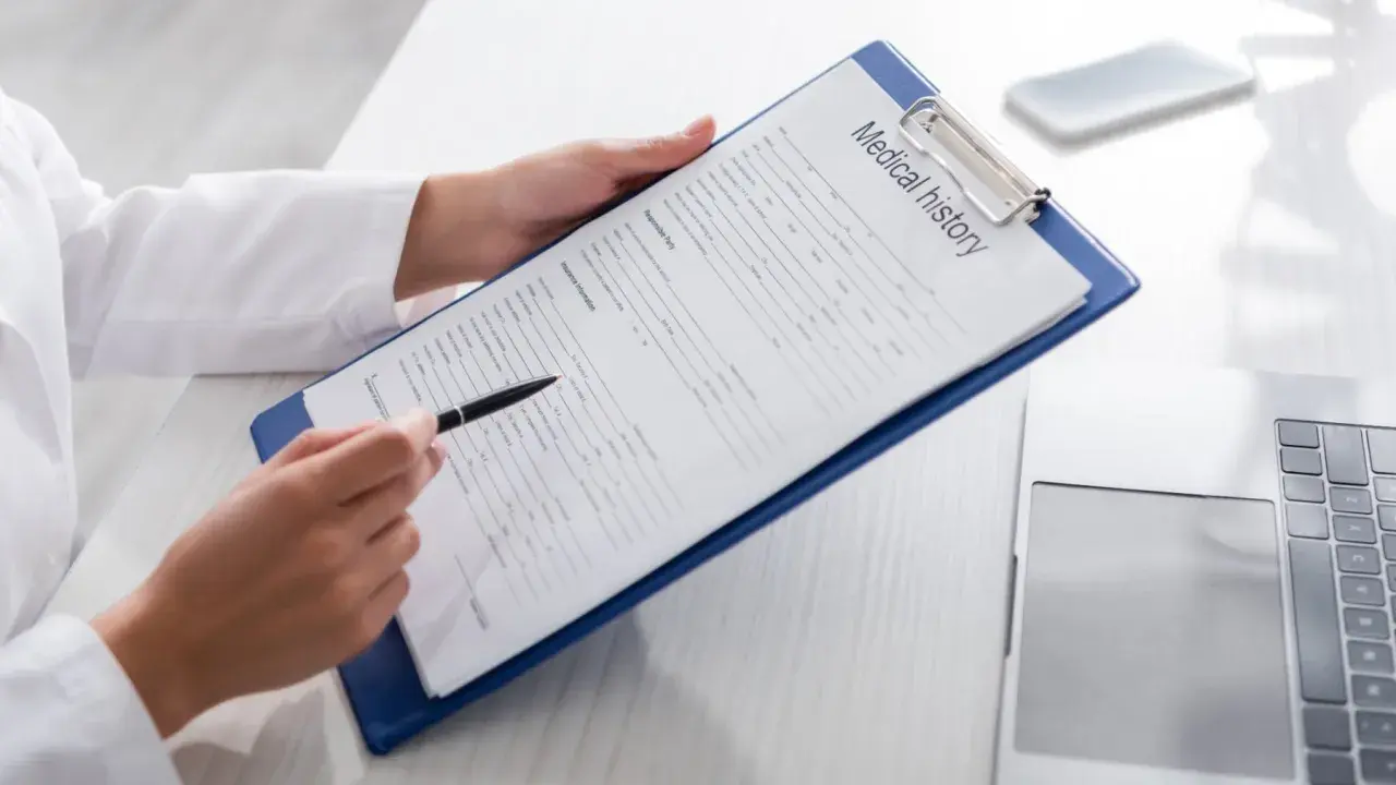 Manos de médico revisan un historial médico en un portapapeles, preparándose para un certificado médico A2.