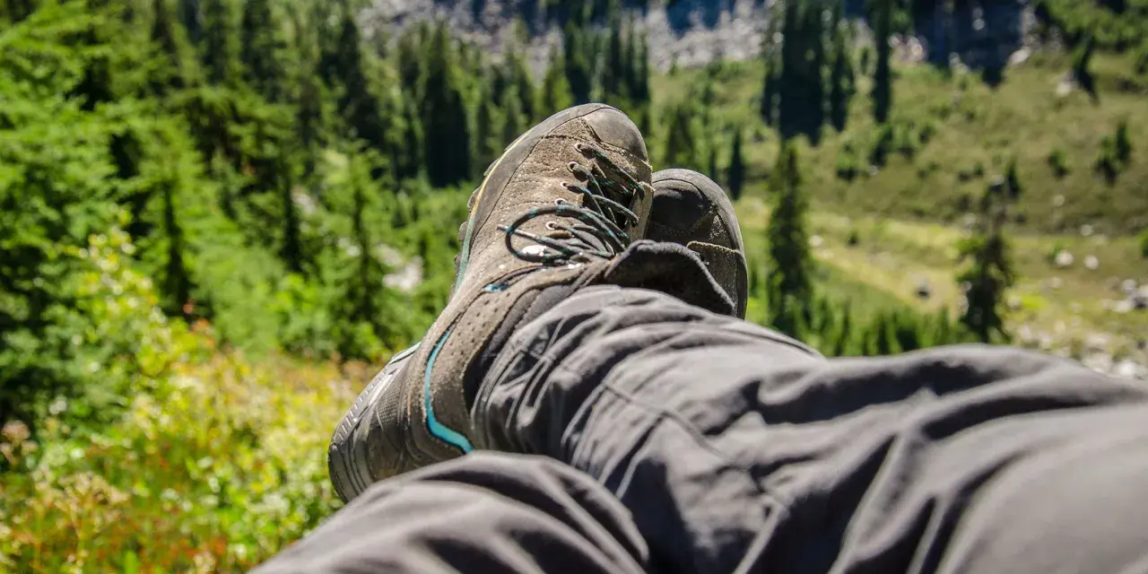 A hiker rests, their well-worn boots laced snugly. This image shows how hiking boots fit, offering comfort and support on the trail.