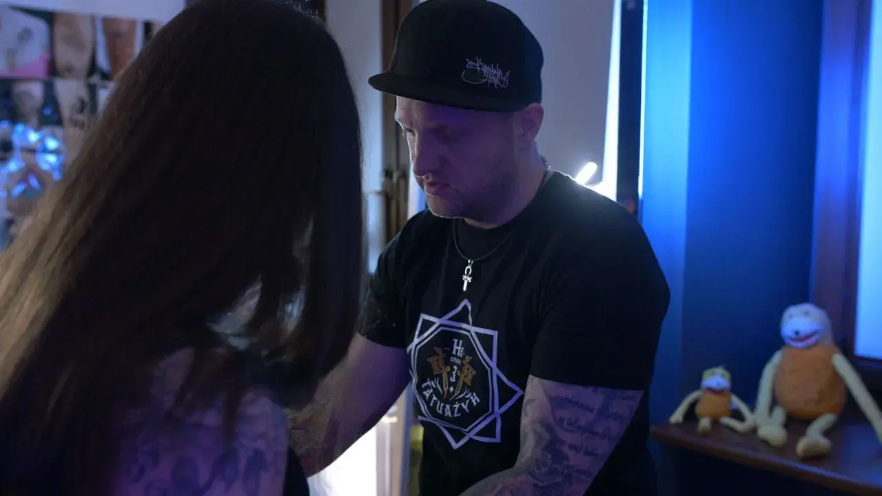 Artysta tatuażu rozmawia z klientką, która przygotowuje się do sesji. Może rozważa leki przeciwbólowe przed tatuażem, by zminimalizować dyskomfort.