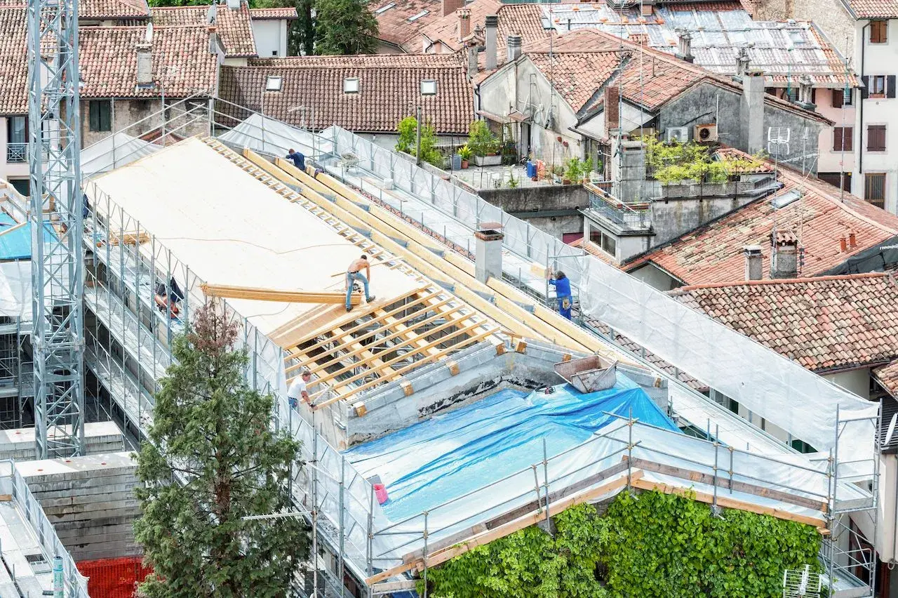 Pracownicy realizują projektowanie dachu, montując drewnianą konstrukcję na budynku.