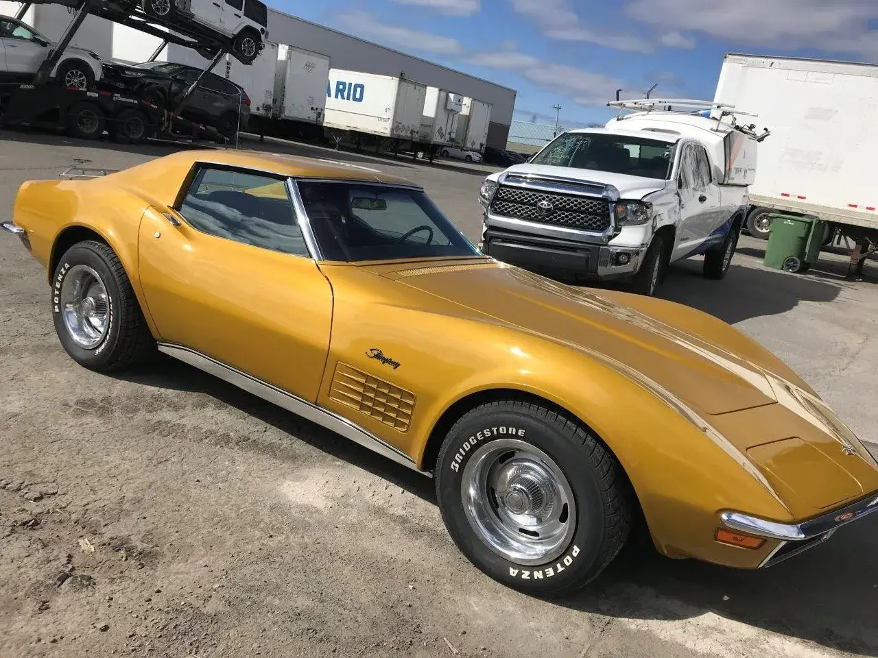 Złoty Chevrolet Corvette Stingray, klasyk wśród amerykańskich samochodów, stoi obok białej ciężarówki.