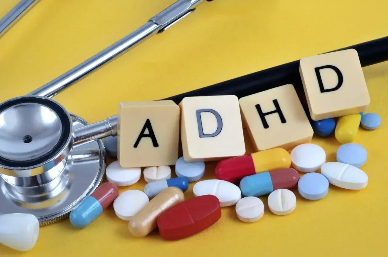 Stetoskop i tabletki symbolizujące leki na ADHD. Litery A, D, H, D ułożone obok.