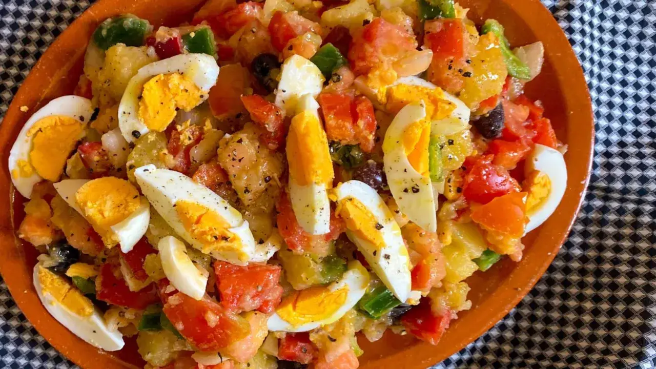 Ensalada campera con patatas, huevos duros, tomate, pimiento y aceitunas. Ingredientes frescos y sabrosos.