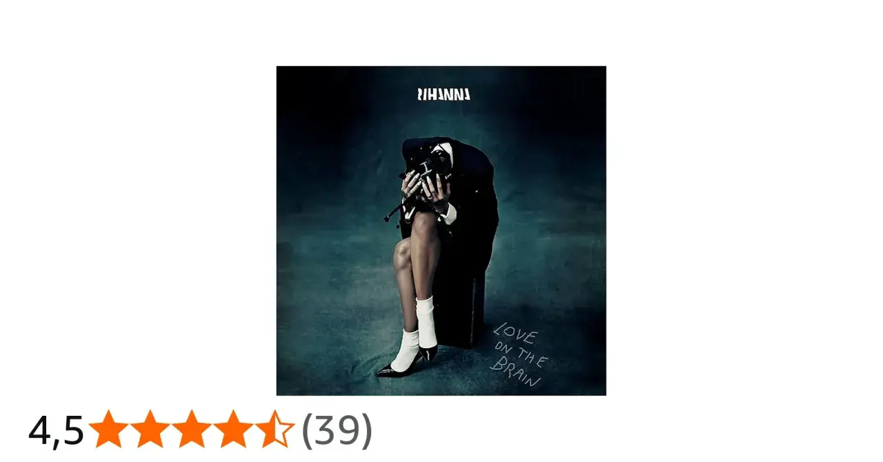 Rihanna w czarnym garniturze, siedząca z głową opuszczoną na dłonie, na tle mrocznego gradientu.