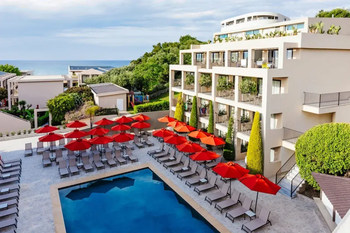 TUI Suneo Tsilivi Admiral: basen z leżakami i parasolami, nowoczesny hotel, morze w tle.