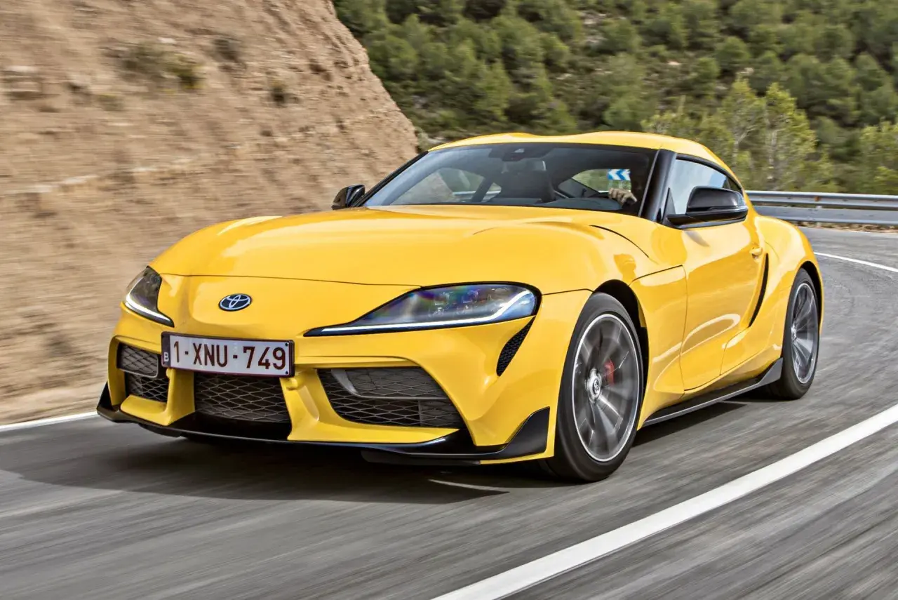 Żółta Toyota Supra pędzi po krętej drodze. Sprawdź aktualną toyota supra cena i poczuj moc!