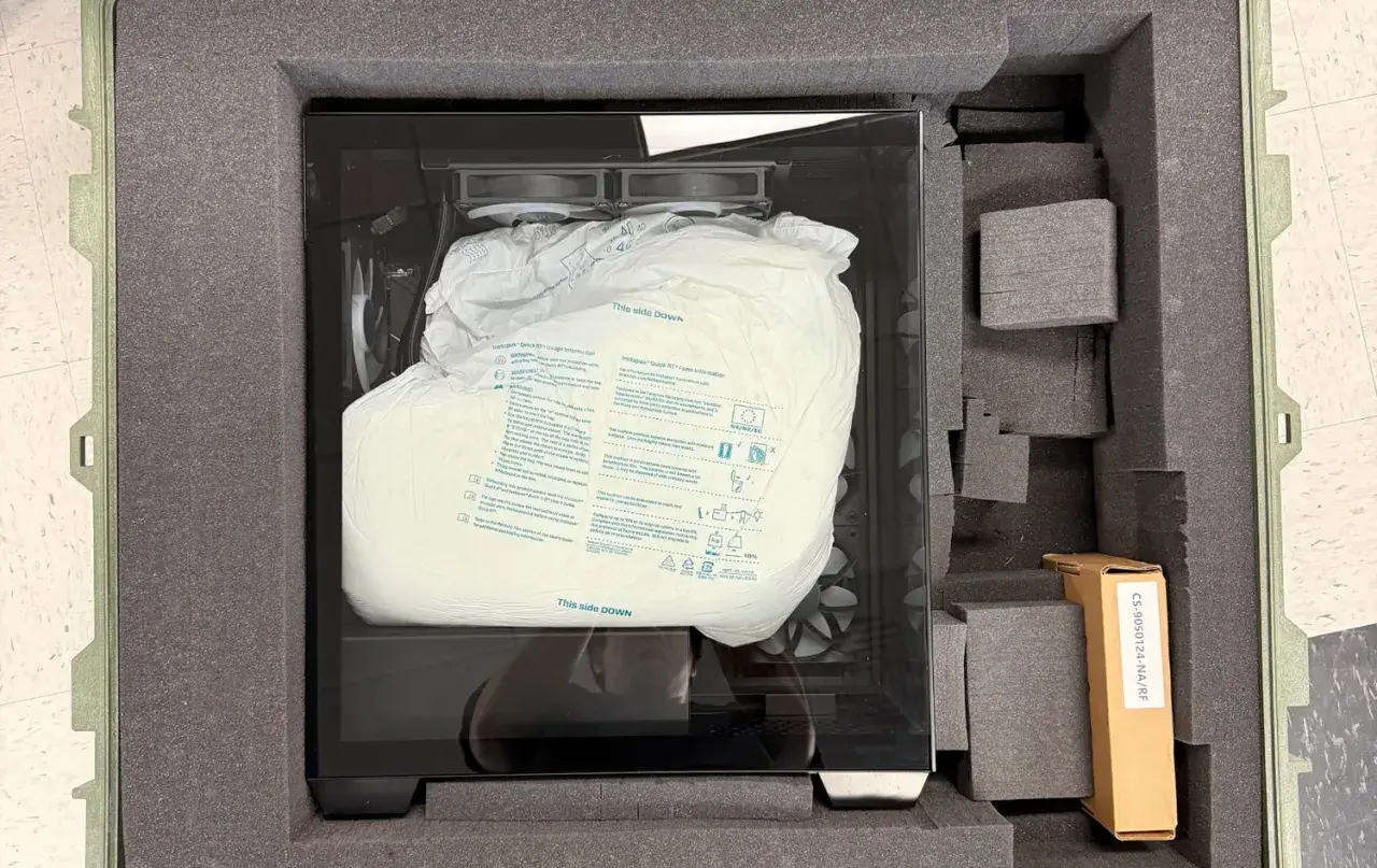 PC sicher verpackt für den Transport in einem gepolsterten Koffer. Die Schutzhülle zeigt "This side DOWN".