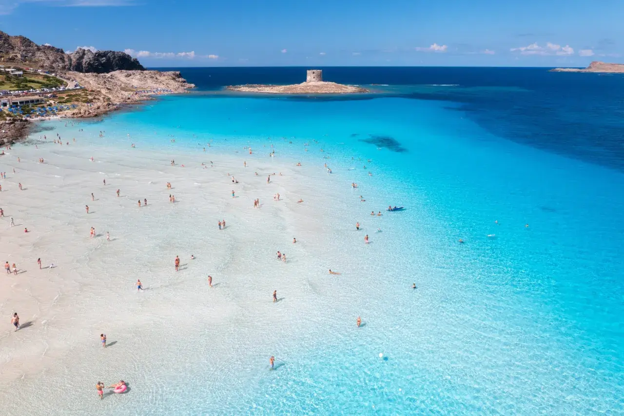 Piękna plaża na Sardynii, idealna na wakacje. Kiedy lecieć na Sardynię? Latem, by cieszyć się słońcem i turkusową wodą.