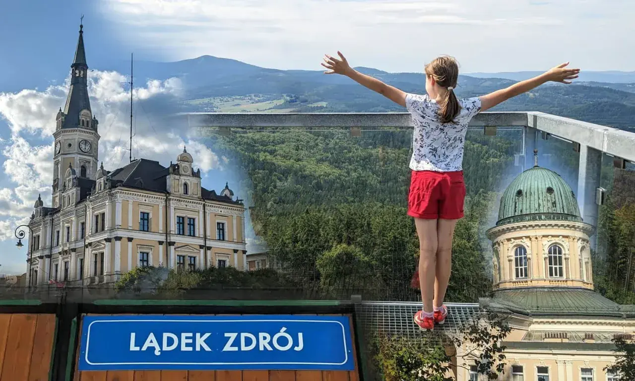 Dziewczynka z rozłożonymi rękami podziwia panoramę Lądka Zdroju z pięknymi budynkami i górami w tle.