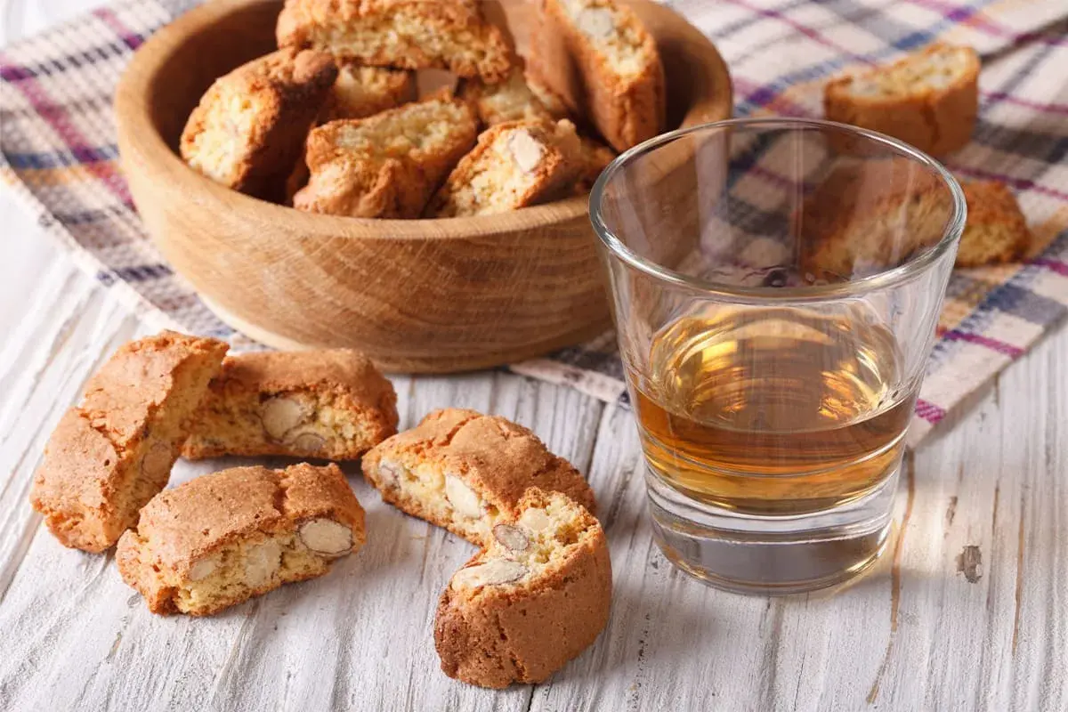 Kieliszek wina Vin Santo i cantucci z migdałami na drewnianym stole.