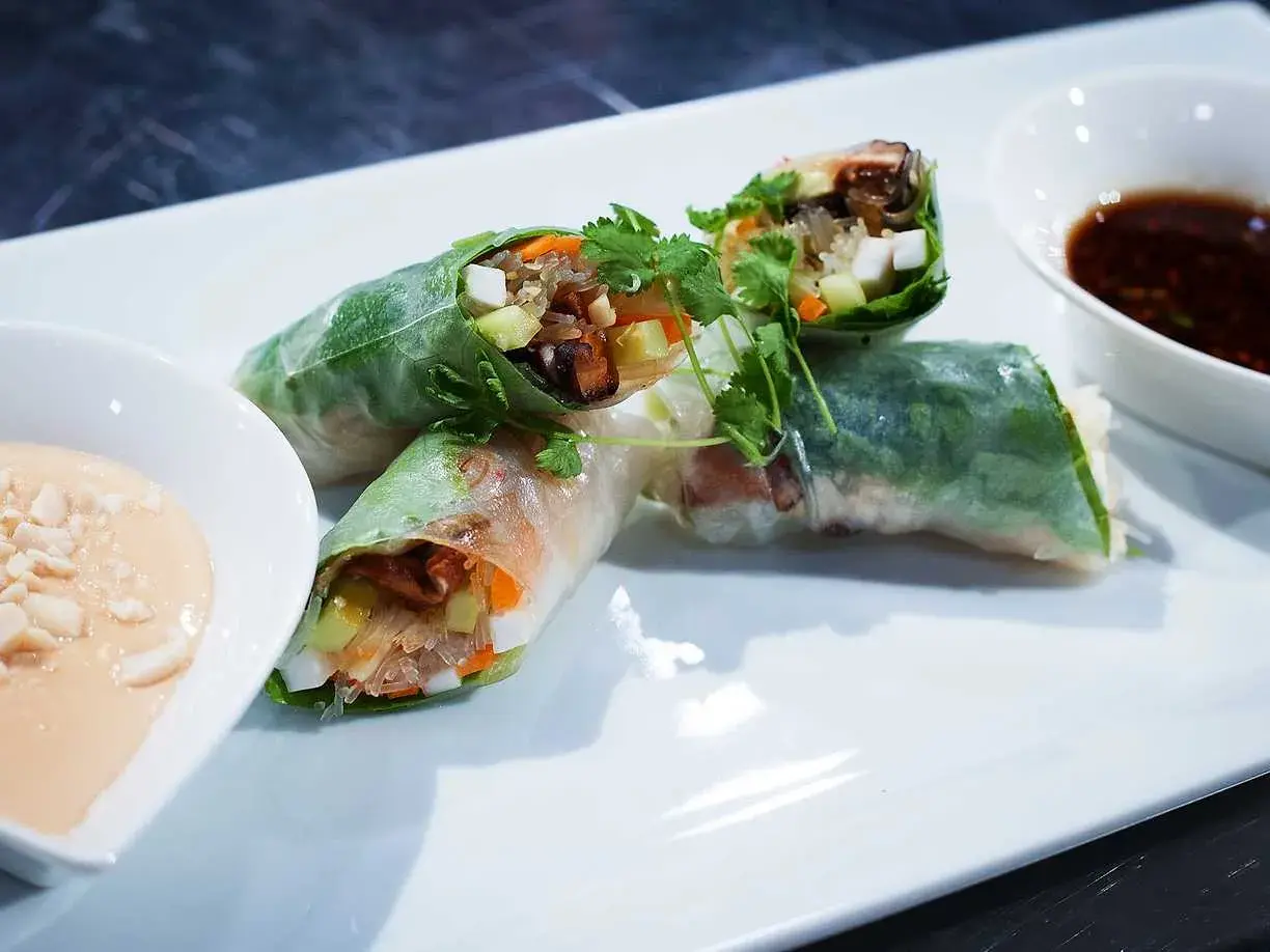 Färska vietnamesiska vårrullar med grönsaker och nudlar, serverade med två dippsåser. Perfekt som förrätt eller lätt måltid.