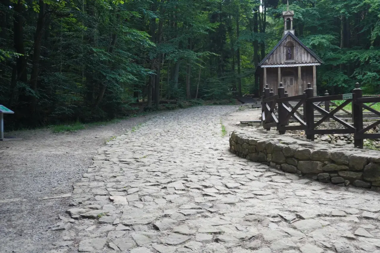 Kamienna ścieżka prowadzi do małej kapliczki w lesie. To wejście na Łysicę, gdzie można poczuć spokój natury.