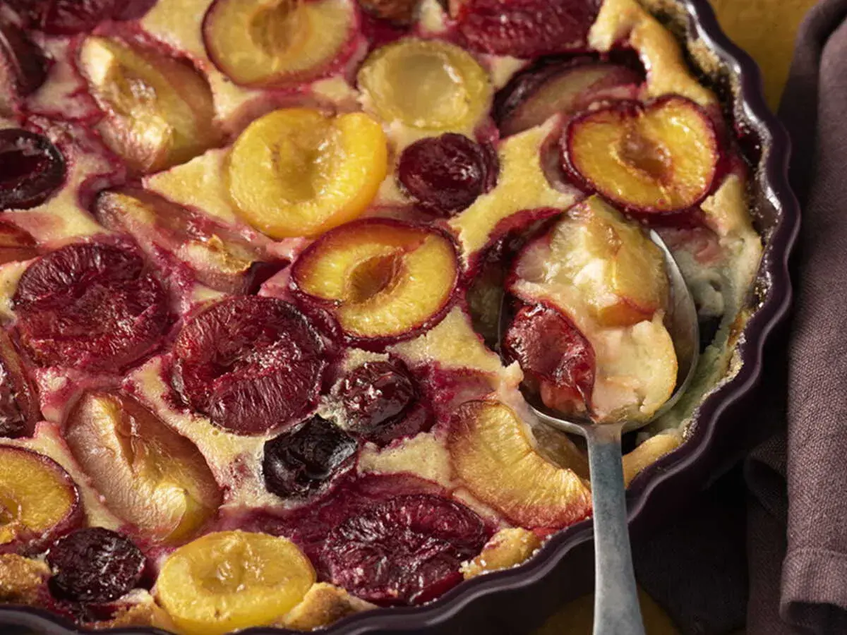 Un délicieux clafoutis aux prunes, aux couleurs vives et à la texture moelleuse, prêt à être dégusté.