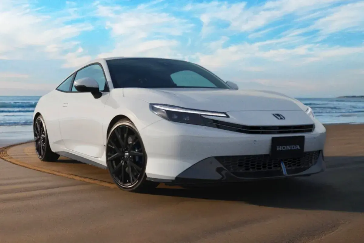 El Honda Prelude 2026 blanco, con su diseño deportivo, se luce en la playa bajo un cielo azul.