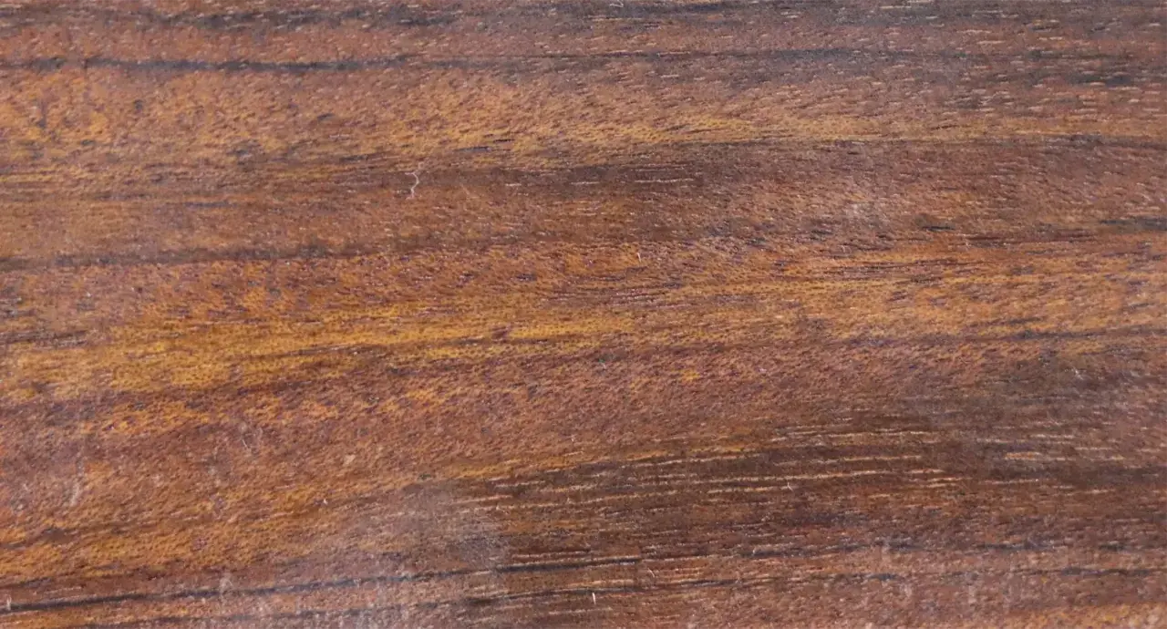 Textura rica de madera mongoy, con vetas oscuras y tonos dorados que evocan la naturaleza.