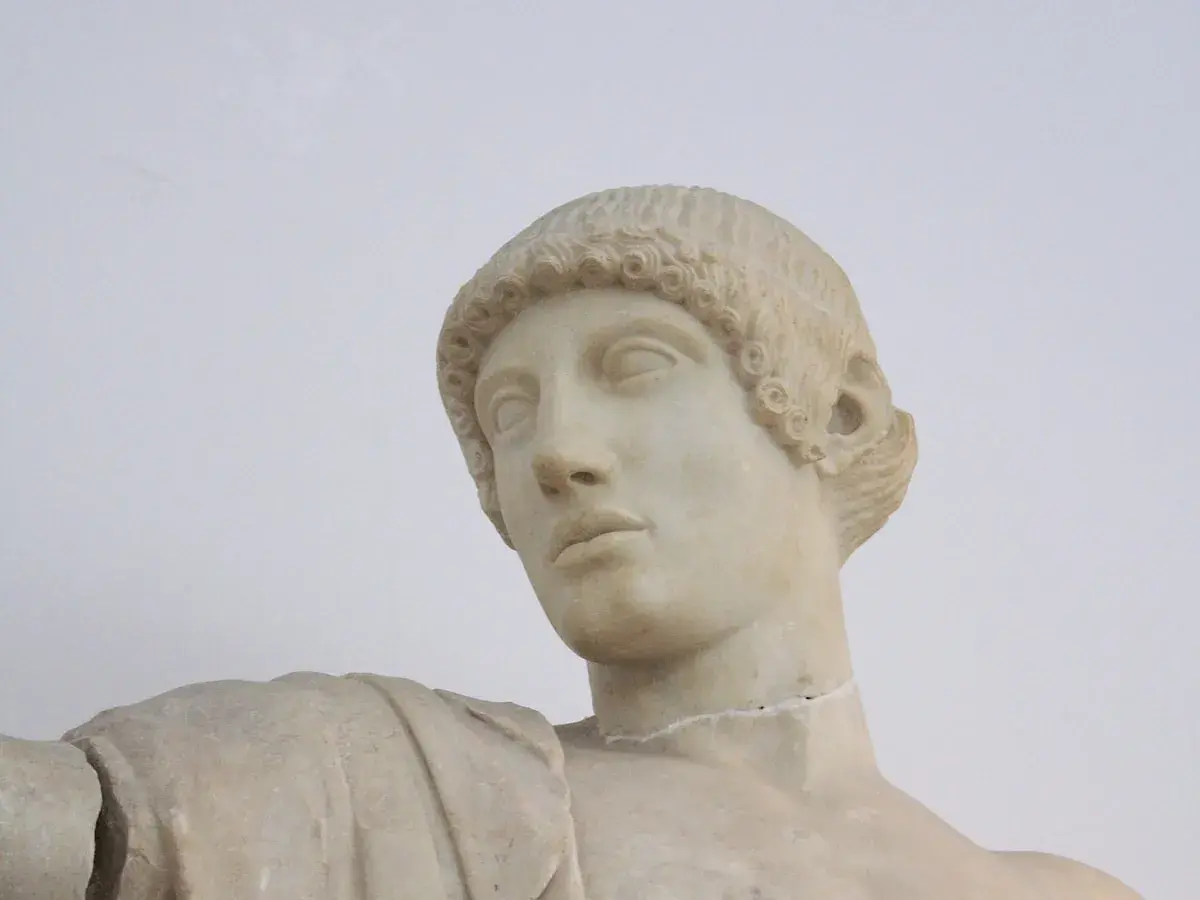 Buste en marbre d'Apollon, dieu grec ou romain, aux boucles caractéristiques et au regard pensif.