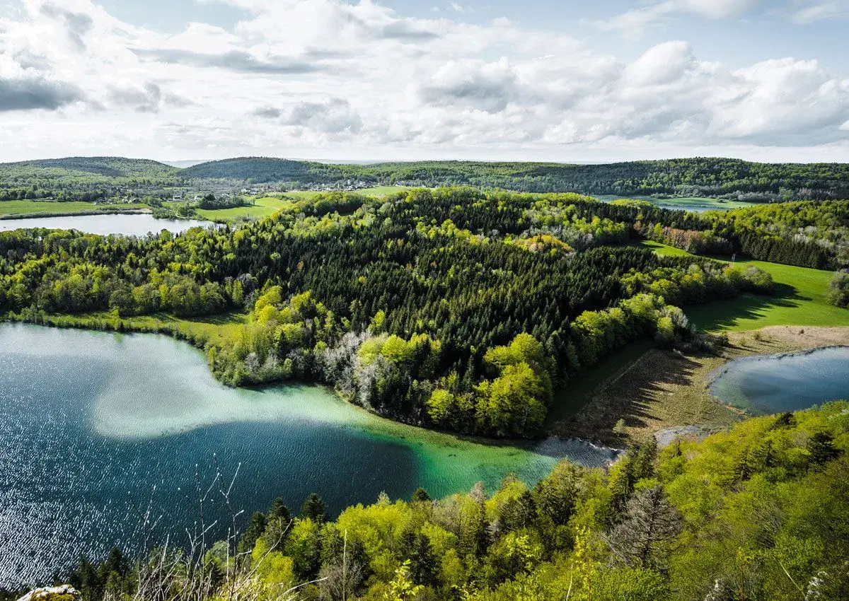 Paysage jurassien avec lacs et forêts verdoyantes, idéal pour une randonnée Jura 5 jours.