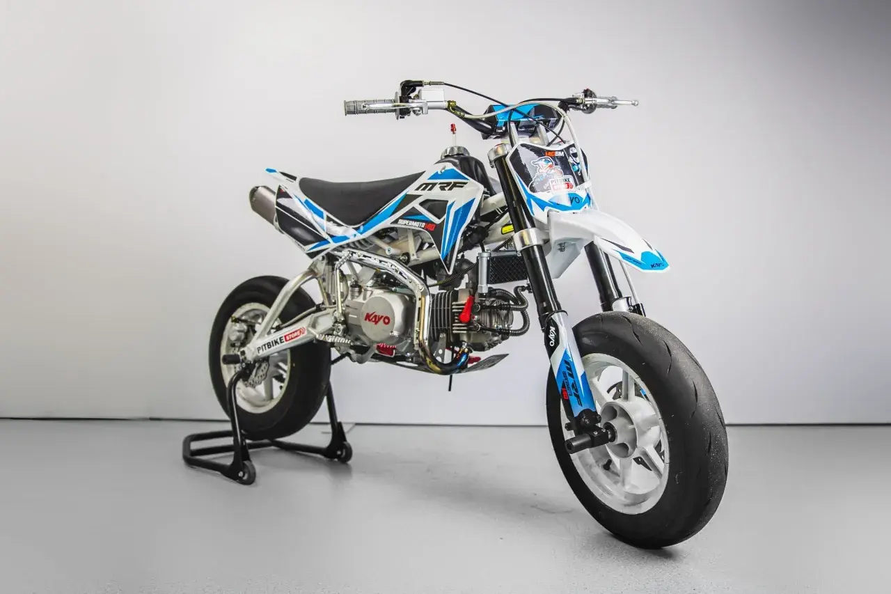 Biało-niebieski pit bike MRF Supermoto 140 na stojaku, z widocznym silnikiem Kayo.