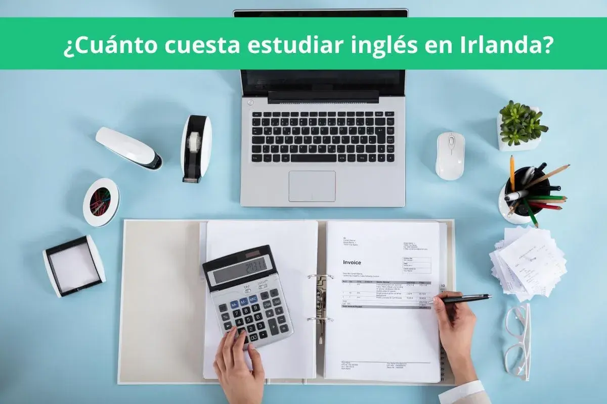 Calculadora, portátil y facturas sobre escritorio azul. Planificando el coste de aprender inglés en Irlanda.