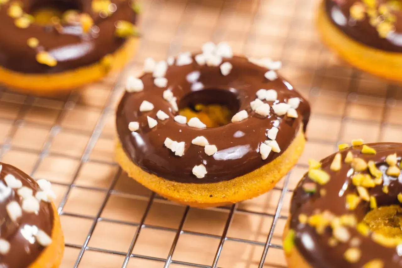 Deliciosos donuts de calabaza cubiertos de chocolate y trocitos crujientes.