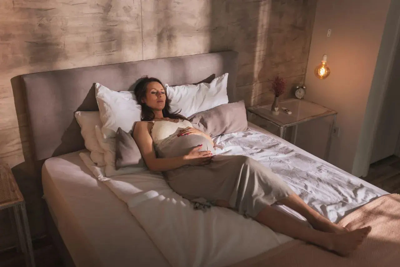 Femme enceinte se repose sur le dos, ventre arrondi, dans une position confortable pour dormir enceinte 1er trimestre.