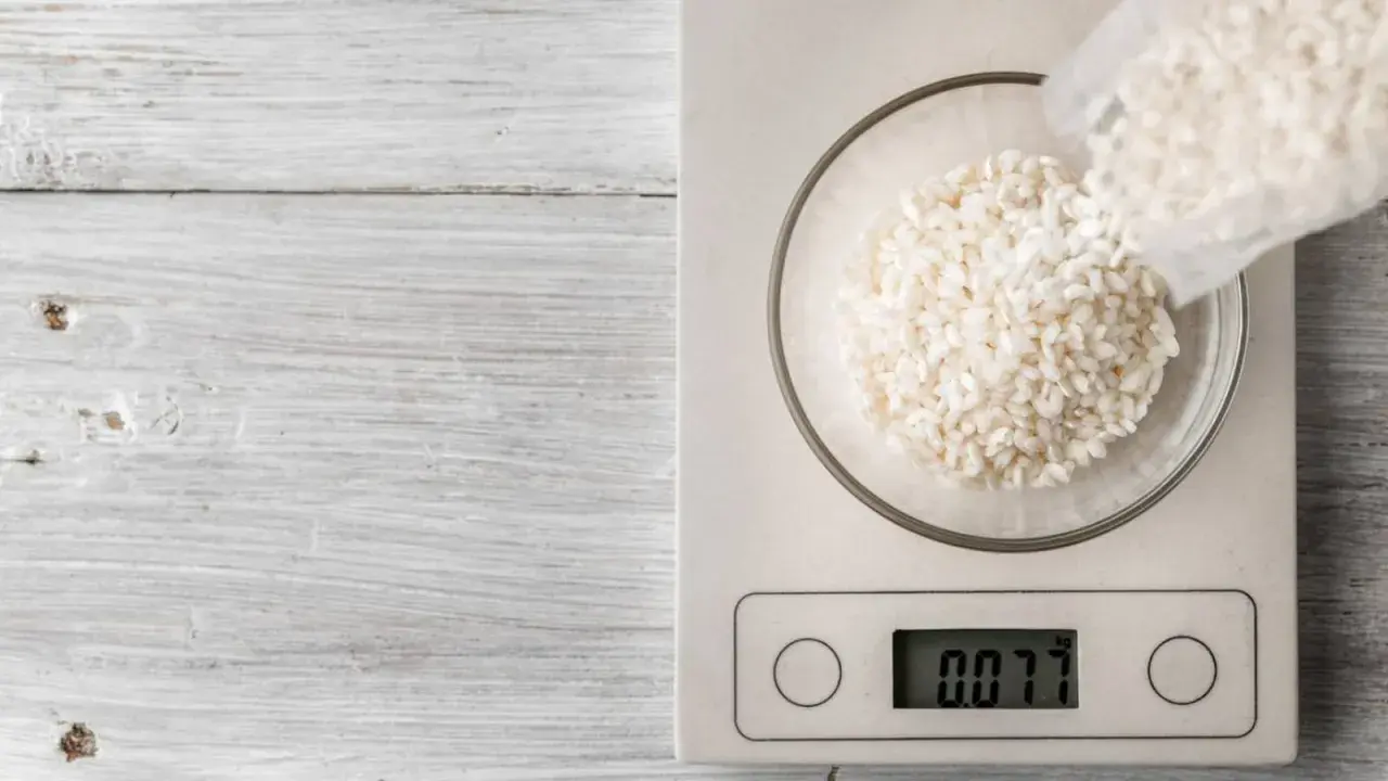 Balanza digital muestra 0.077 kg de arroz en un bol. Ideal para calcular cuánto arroz por persona.