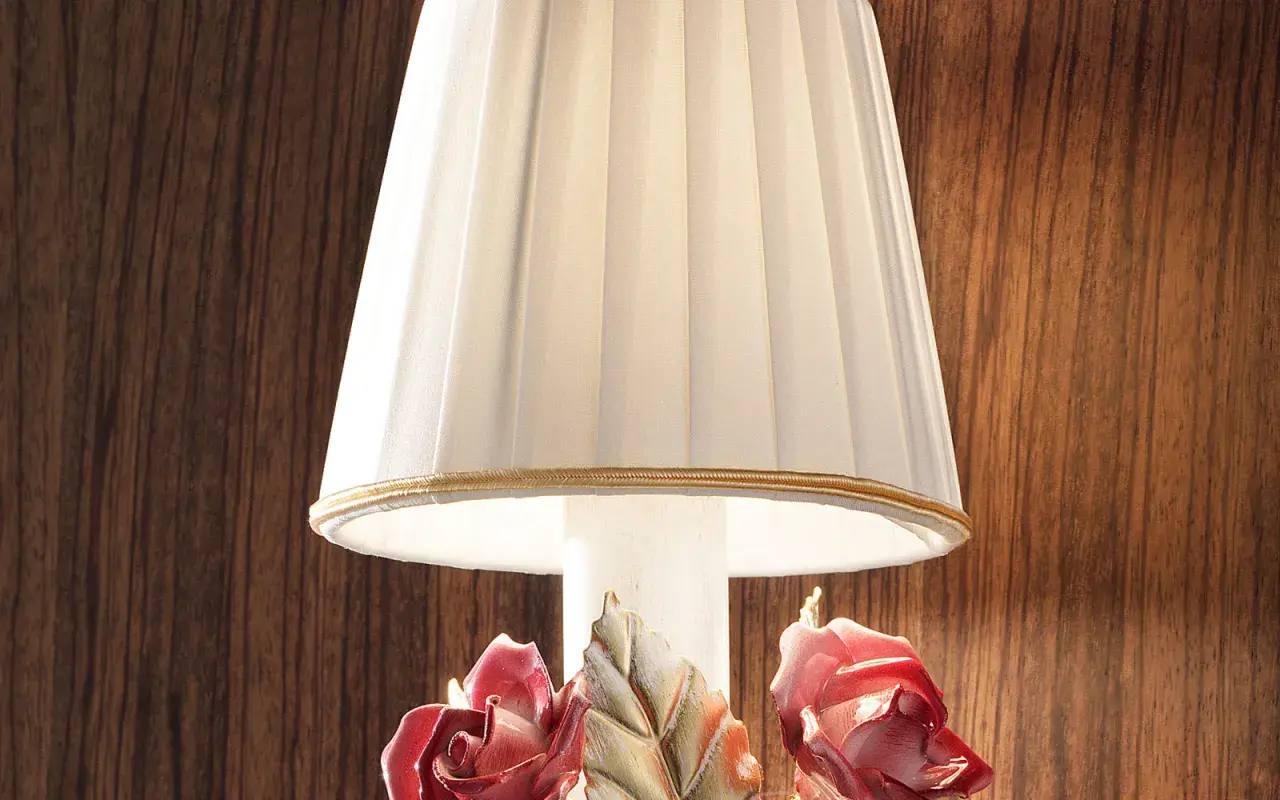 Elegancka lampka nocna z plisowanym abażurem i ceramicznymi różami u podstawy.
