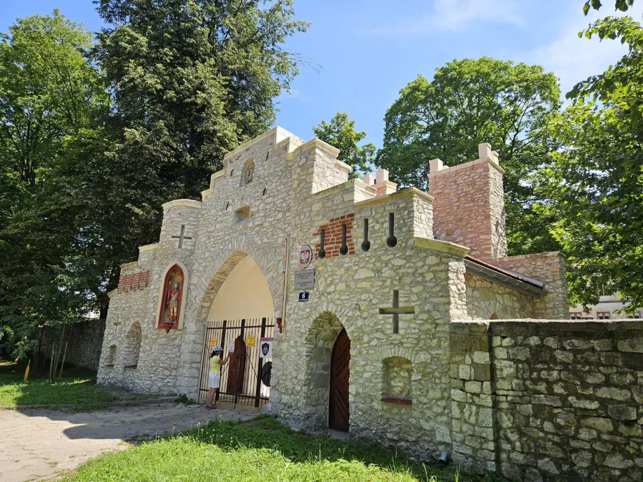 Kamienna brama z krzyżami i figurą świętego, przypominająca wejście do puszczy dulowskiej.