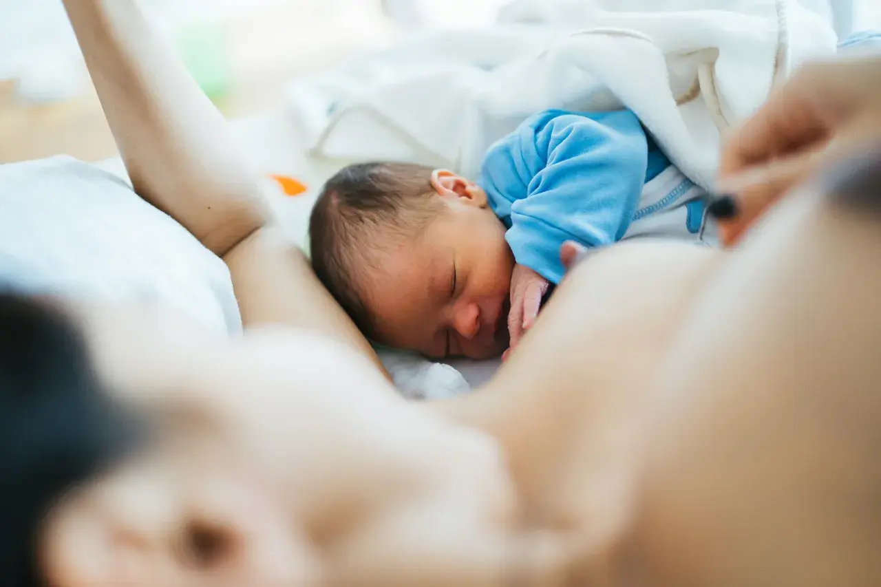 Malutki noworodek śpi wtulony w mamę. Jego brzuszek jest taki okrągły i słodki, jak u każdego niemowlaka.