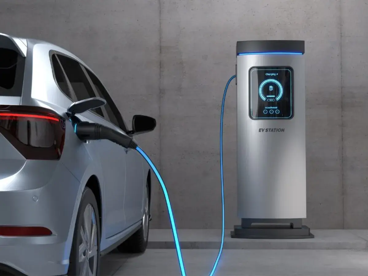 Srebrny elektryk podłączony do stacji ładowania. Sprawdź, jaki jest koszt ładowania elektryka i zacznij oszczędzać.