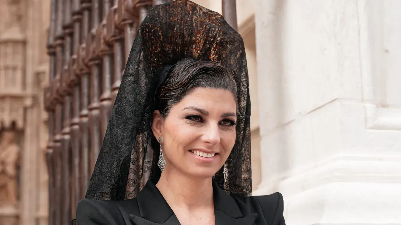 Mujer con peinado boda gitana, velo de encaje negro y pendientes largos. Sonríe con elegancia.