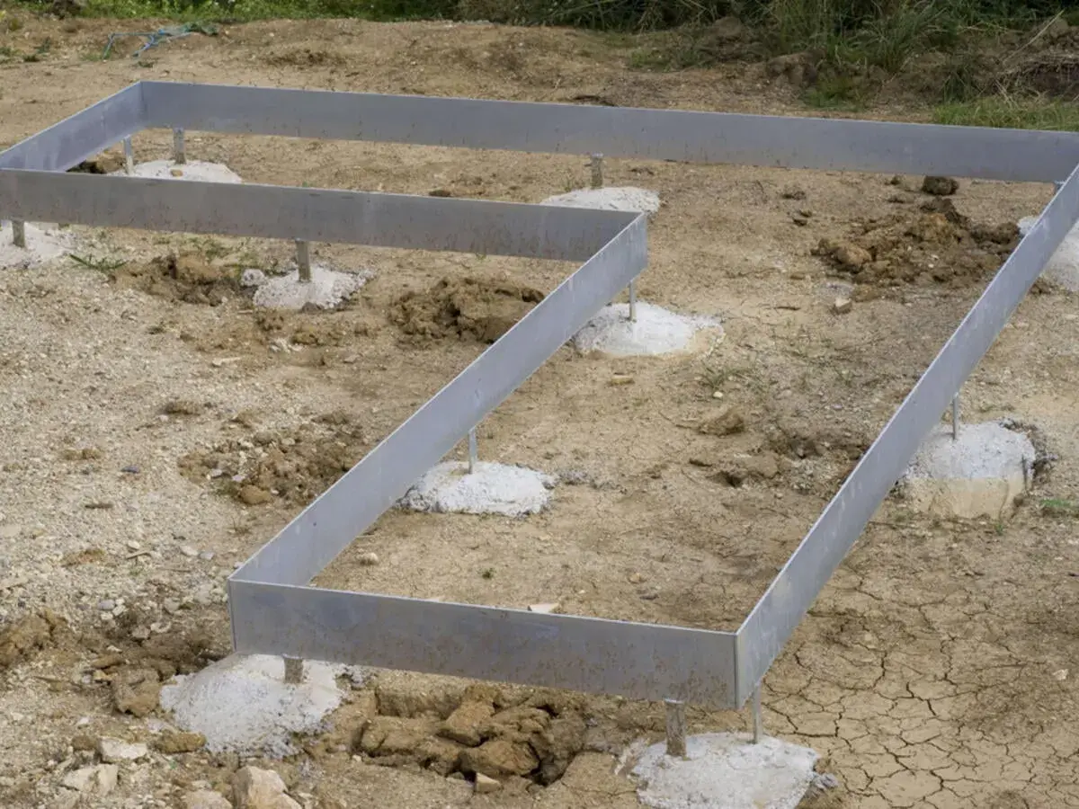 Metallrahmen auf Betonfundamenten für ein neues Haus. Das punkt fundament ist vorbereitet.