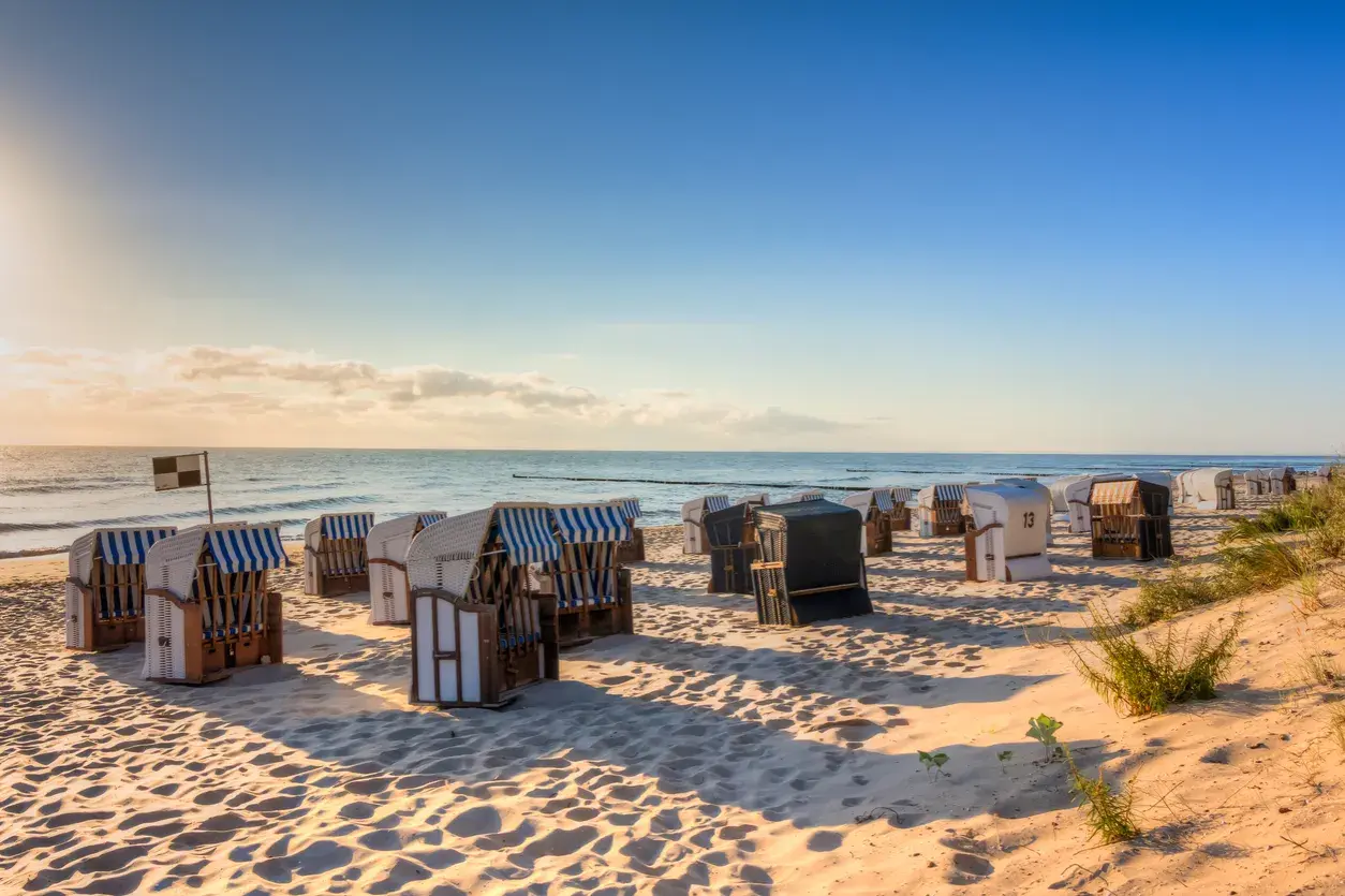Reihe von Strandkörben am Strand Deutschland, mit Blick auf das Meer und den blauen Himmel.