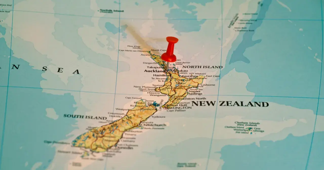 Czerwony pinezka zaznacza Nową Zelandię na mapie. To państwo wyspiarskie, które geograficznie należy do Oceanii, choć kulturowo i politycznie często kojarzone jest z Australią, która leży na kontynencie australijskim.