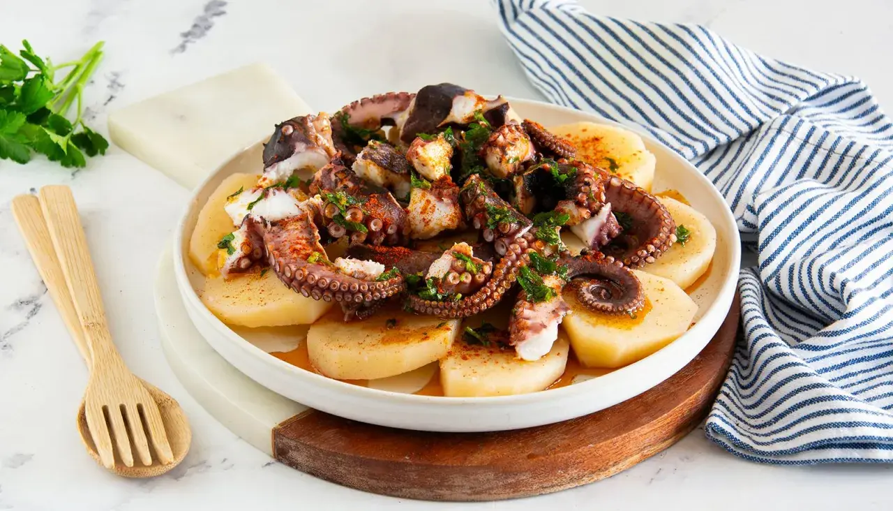 Piatto di polpo alla gallega, con tentacoli succulenti su patate affettate, condito con paprika e prezzemolo fresco.