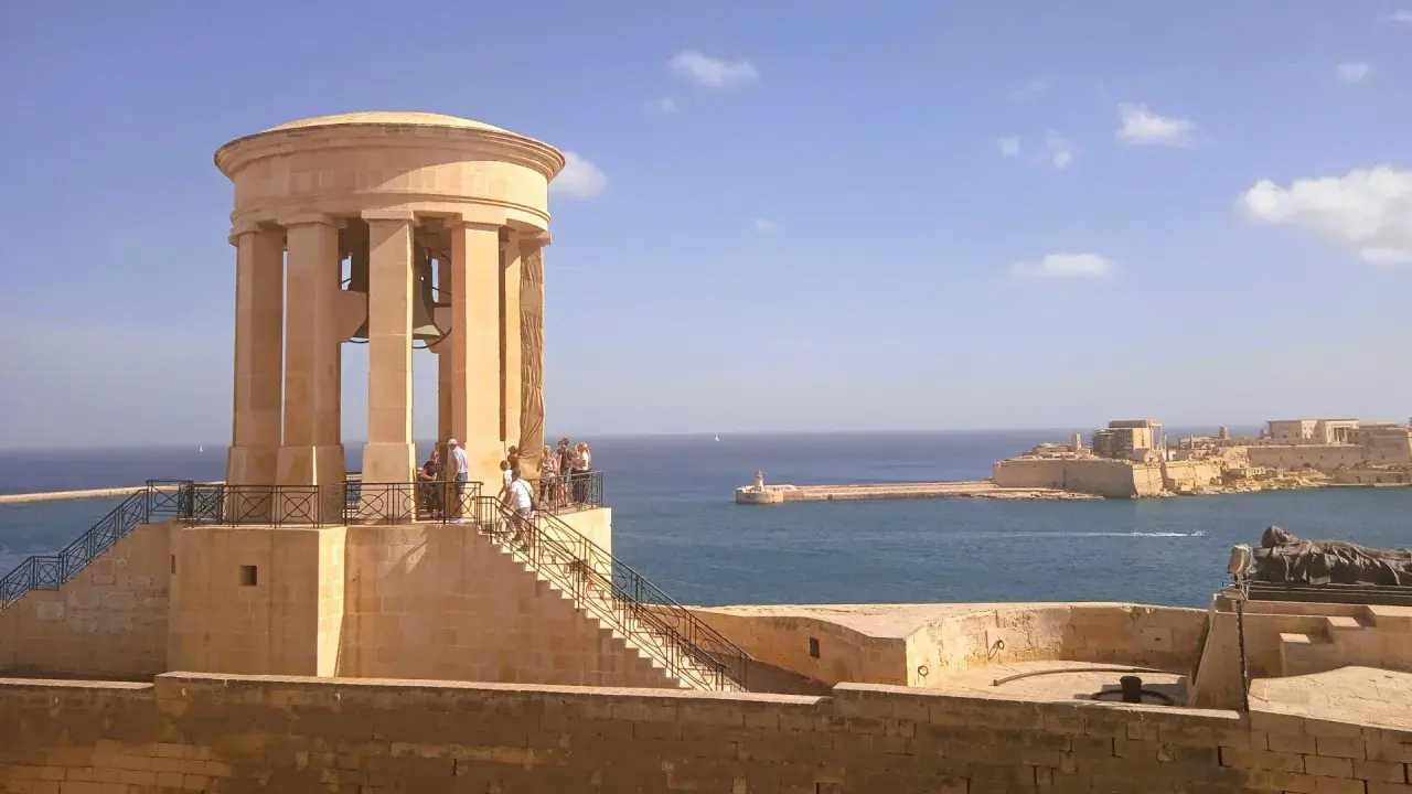 Malta, kwiecień: słoneczna pogoda nad portem, widok na zabytkową wieżę z dzwonami i fortyfikacje.