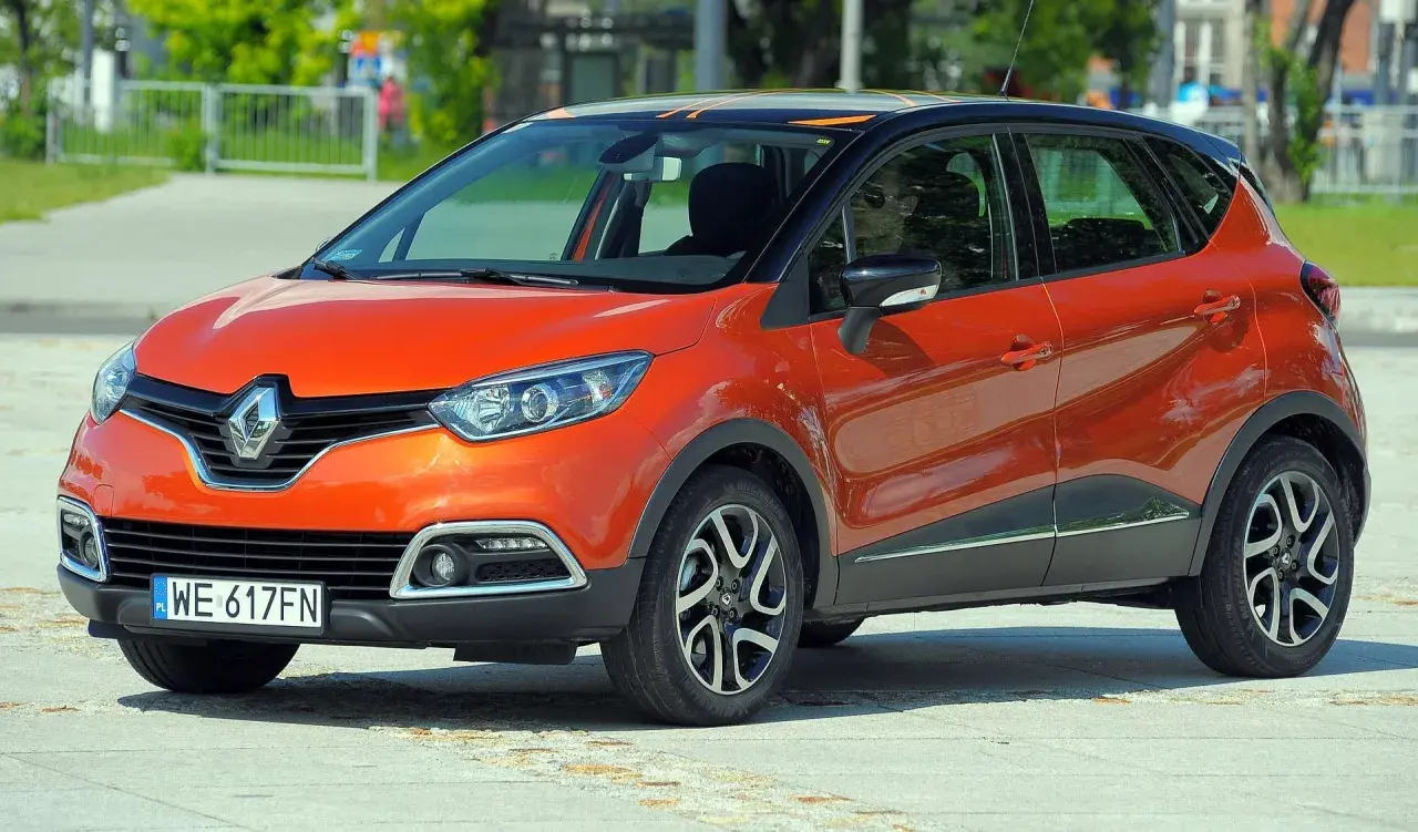 Pomarańczowy Renault Captur 2015 z czarnym dachem i pomarańczowymi akcentami stoi na placu.