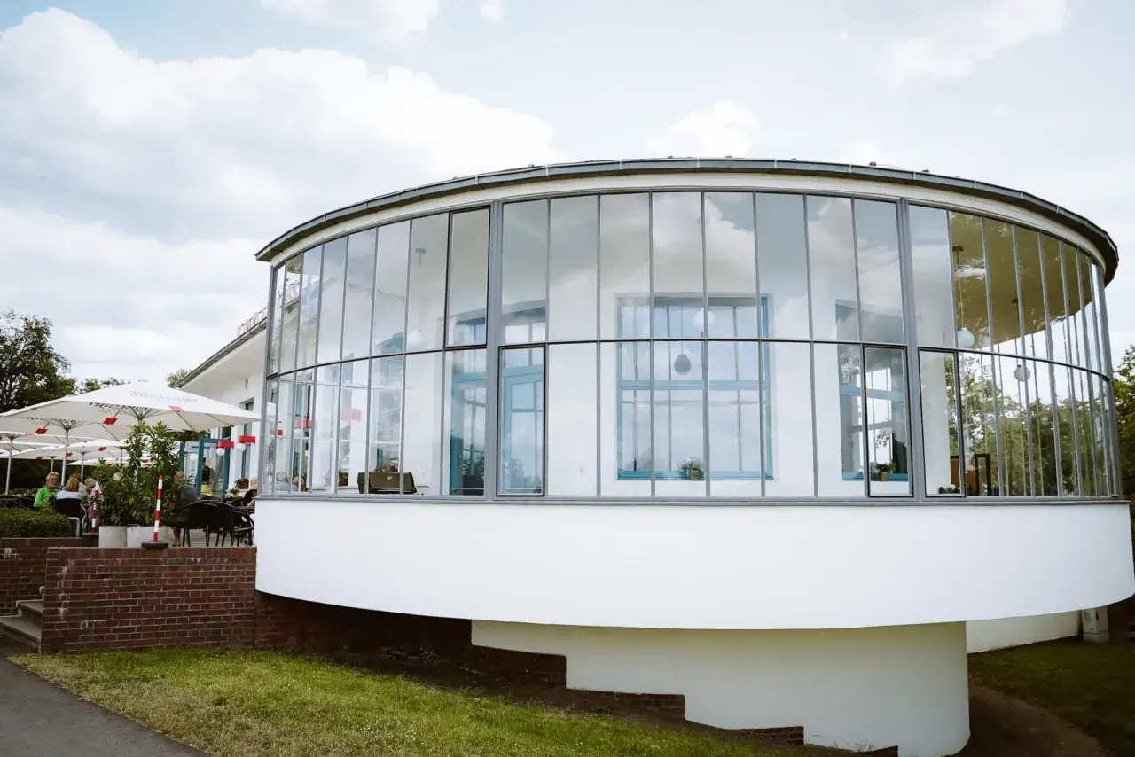 Ein modernes Gebäude mit runden Glasfronten, das an einen Aussichtsturm erinnert. Hier finden sich sicher einige Geheimtipps Dessau.