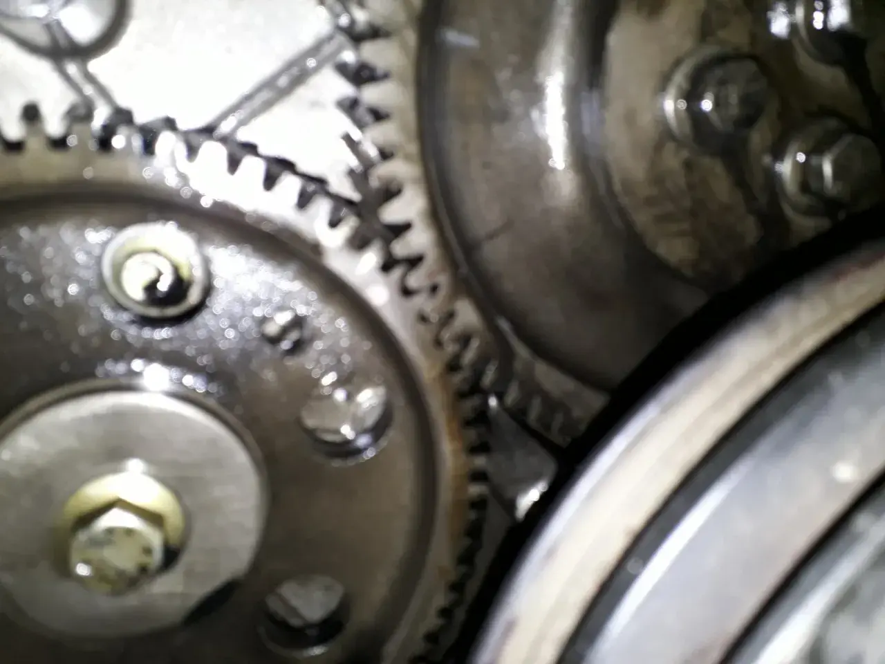 Zbliżenie na mechanizm zębatek, kluczowe dla ustawienia pompy wtryskowej Perkins 4. Widoczne śruby i smar.