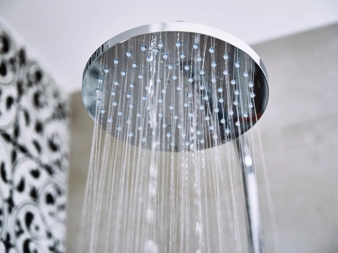 Acqua che scorre da un soffione doccia moderno, un promemoria per sapere come pulire il soffione della doccia per un getto perfetto.