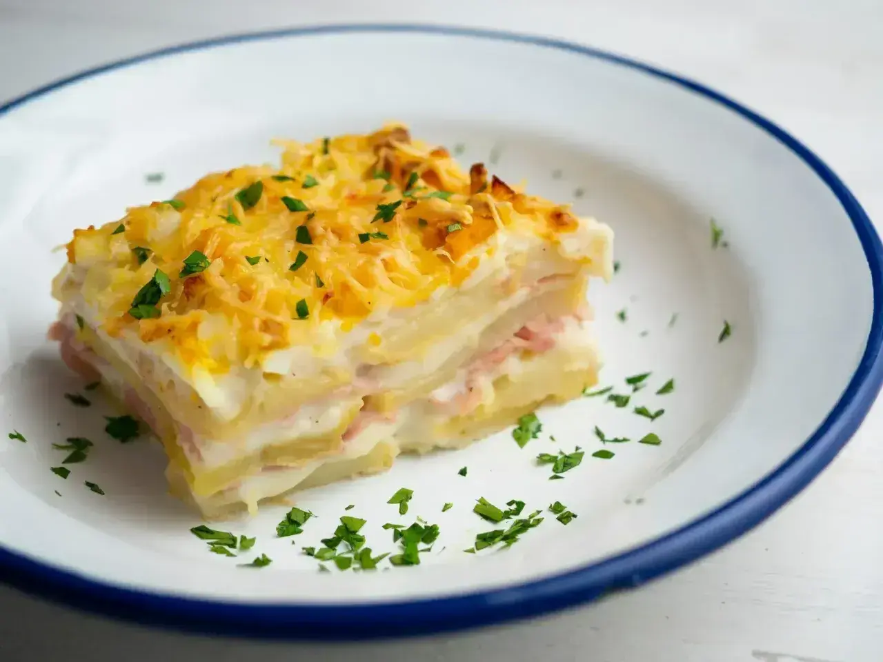 Pyszny kawałek zapiekanki ziemniaczanej z szynką i serem, idealny na obiad. Ten przepis na lasagne ziemniaczaną zachwyci każdego!