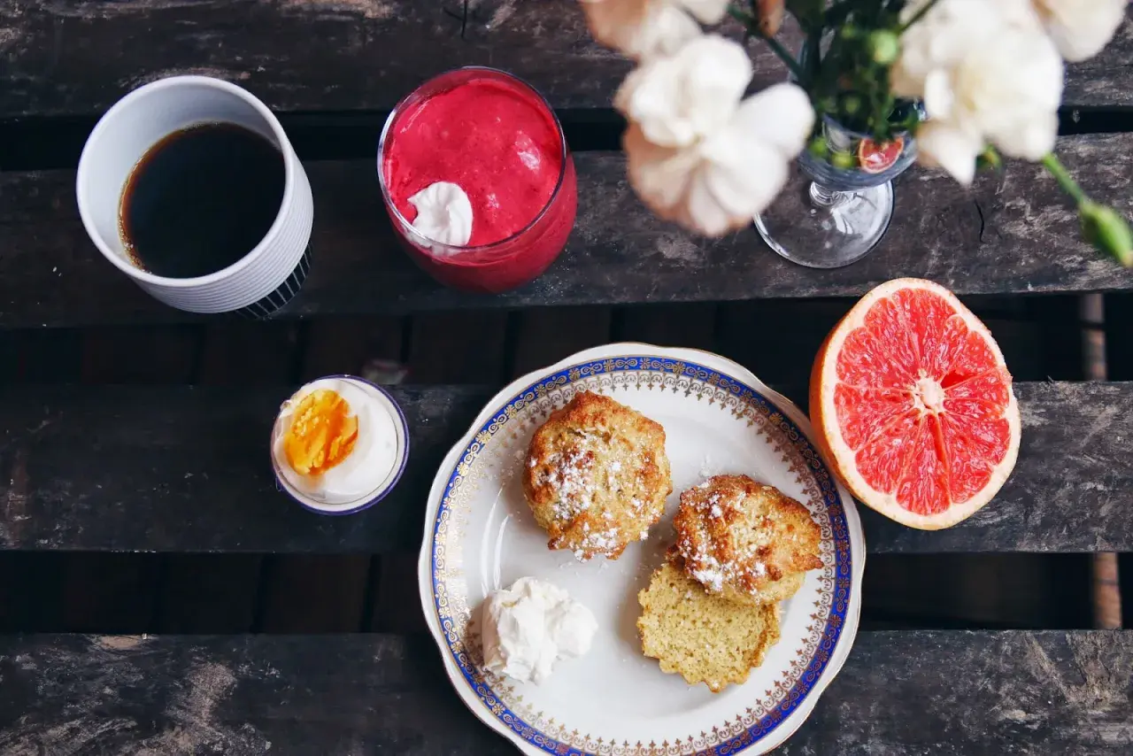 Frukost med kaffe, en rosa smoothie, ett kokt ägg, grapefrukt och nybakade mandelscones.