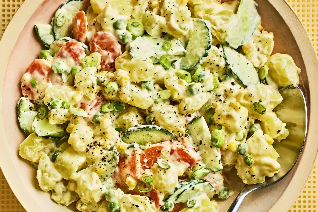 A creamy Japanese potato salad with chunks of potato, cucumber, peas, and carrots, garnished with green onions and black pepper.