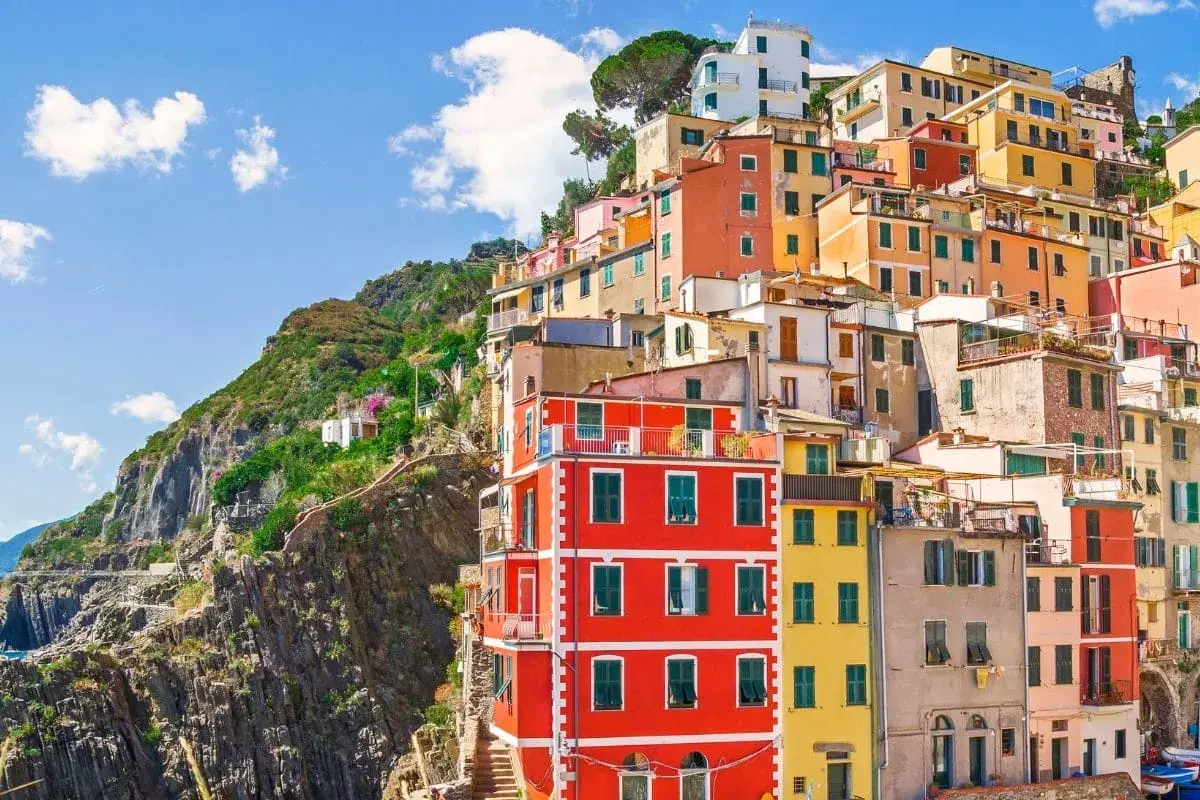 Färgstarka hus klättrar uppför en brant sluttning vid kusten i Italien. En vy som inbjuder till dricks i Italien.