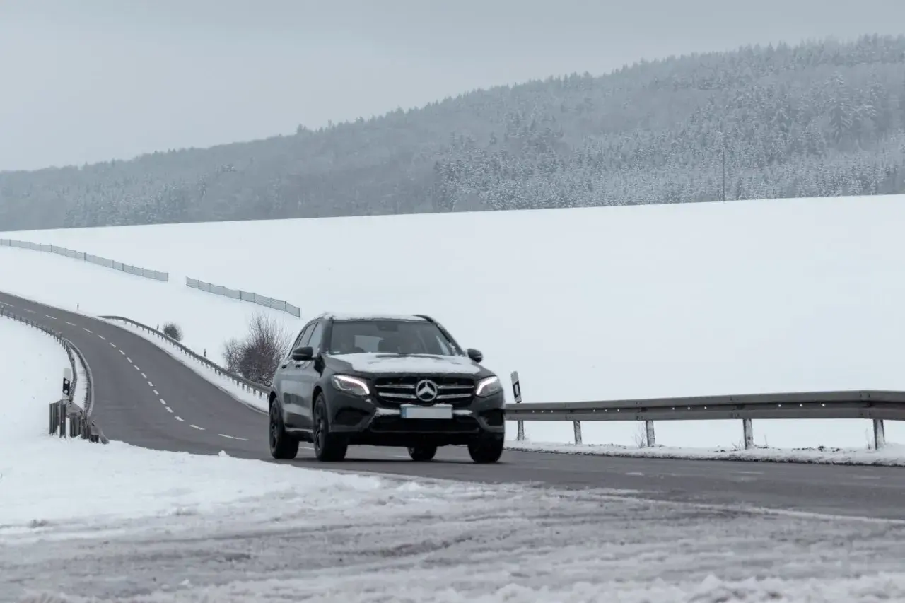 Czarny Mercedes GLE jedzie po ośnieżonej drodze. Jego wymiary pozwalają na pewne poruszanie się w trudnych warunkach.