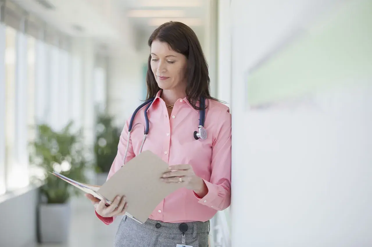 Médecin consultant un dossier, peut-être pour un deuxième avis médical et son remboursement.